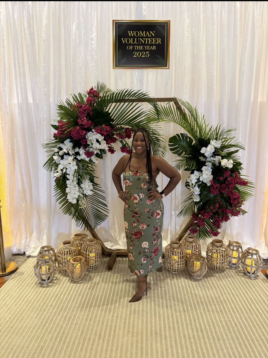 Brittanny at the Junior League of Boca Raton's Woman Volunteer of the Year 2025 event, in front of a floral arch